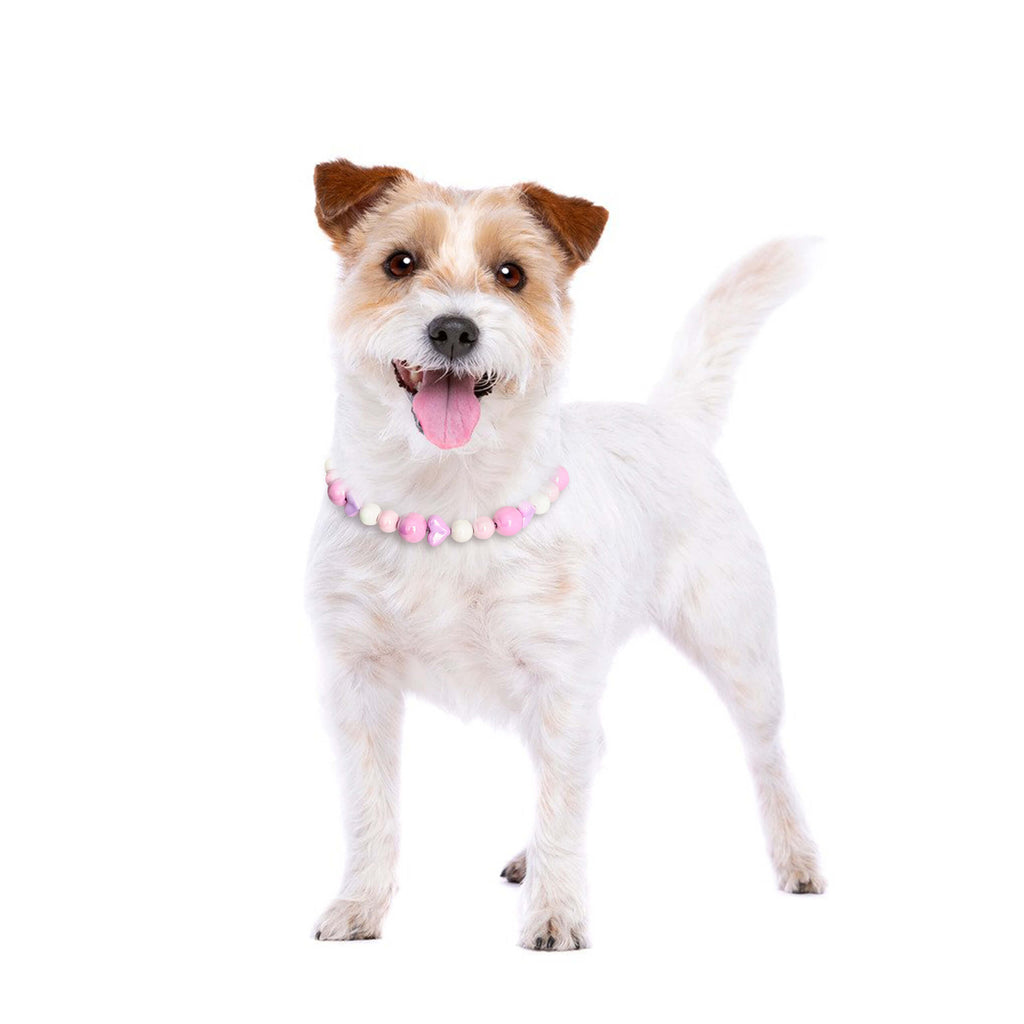 Dog smiling while wearing the JOGIA pink heart beaded collar in a bright studio portrait.
