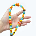 Close-up of JOGIA star-themed beads held in hand, showing bright colors and star charm.
