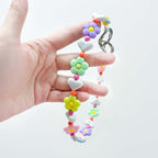 Close-up of JOGIA floral beads held in hand, showing pastel flower details.