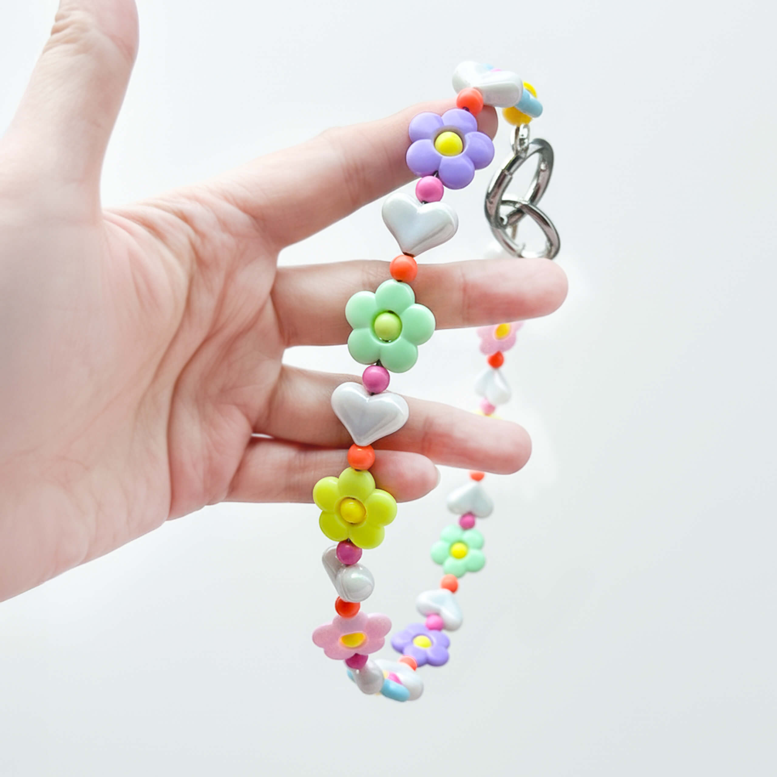 Close-up of JOGIA floral beads held in hand, showing pastel flower details.